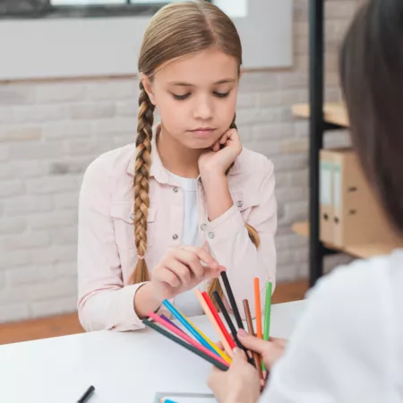 sad-little-girl-choosing-colored-pencils-hold-by-female-psychologist